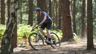 Man riding a Marin DSX 1 bike on a trail through the woods, United Kingdom.