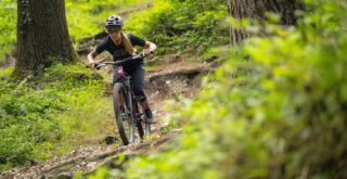 Marin rider Juliet Elliott riding a Rift Zone XR AXS on a trail in the forest, UK.