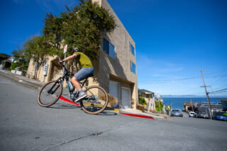 man riding uphill in residential area with blue skies